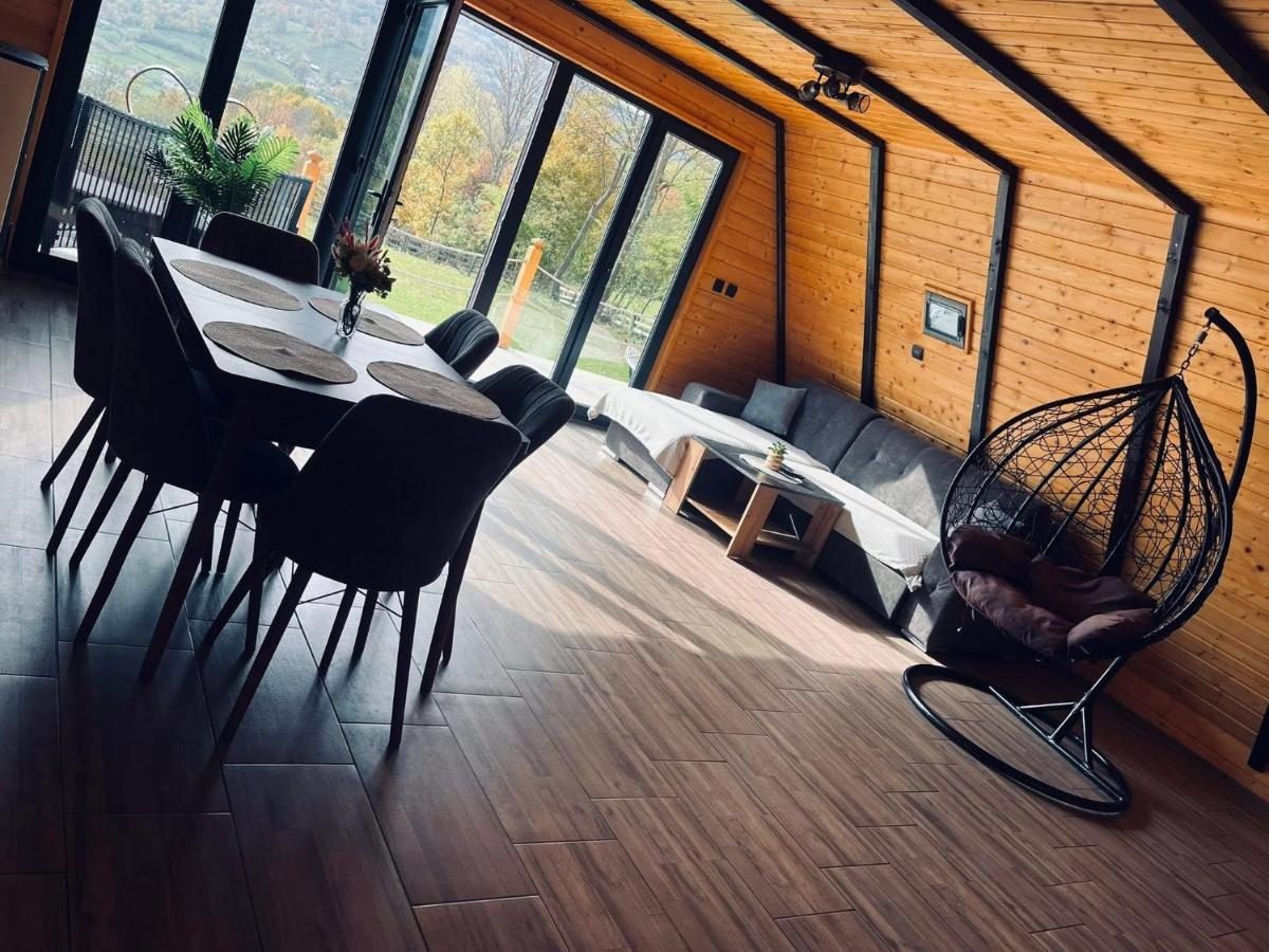 Livingul cu masa, canapeaua și geamurile mari spre curte